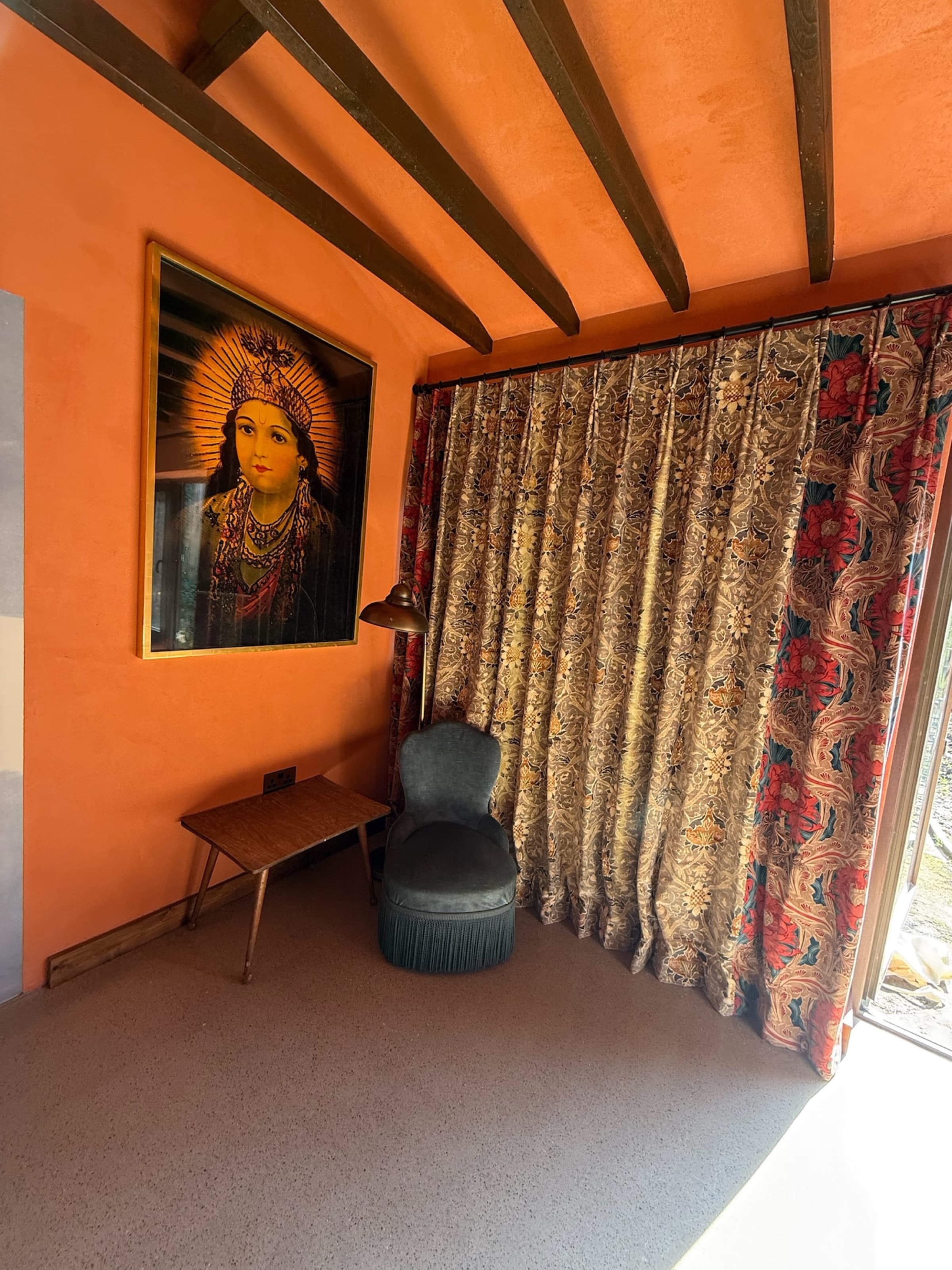 Terracotta corner with framed icon artwork, patterned curtains, velvet chair