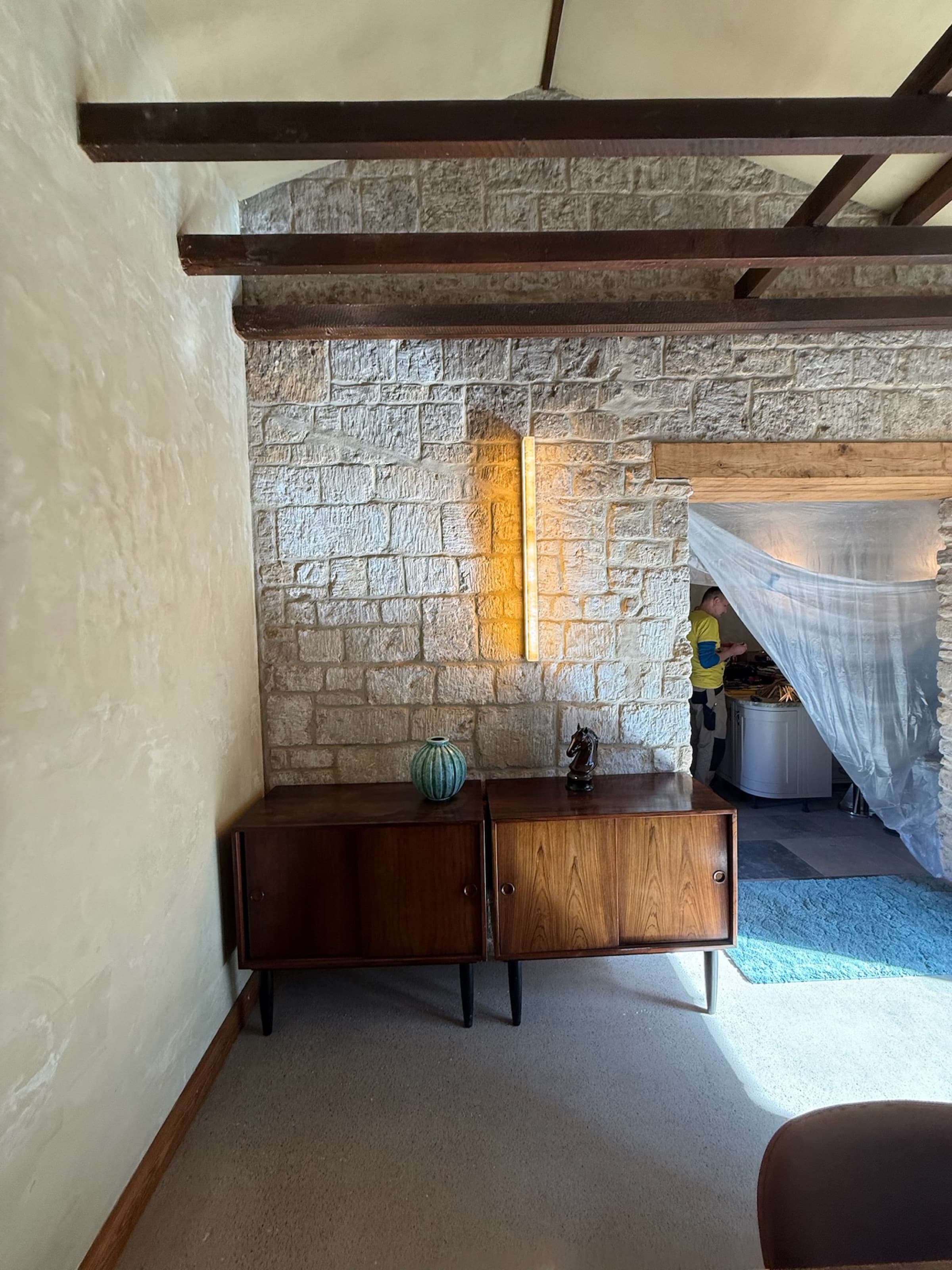 Lounge, stone wall and sideboard, glimpse through to bedroom